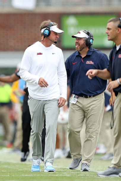 Two football coaches engaging in conversation on the sidelines during a game.