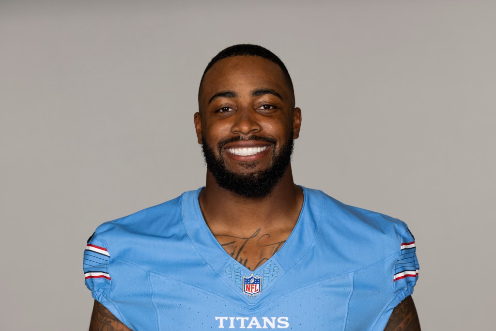 Portrait of a smiling male football player in a light blue NFL jersey with 'TITANS' written on it.