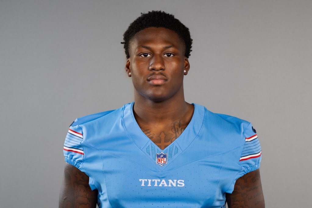 A young male football player wearing a light blue jersey with 'TITANS' printed on it, posing against a gray background.