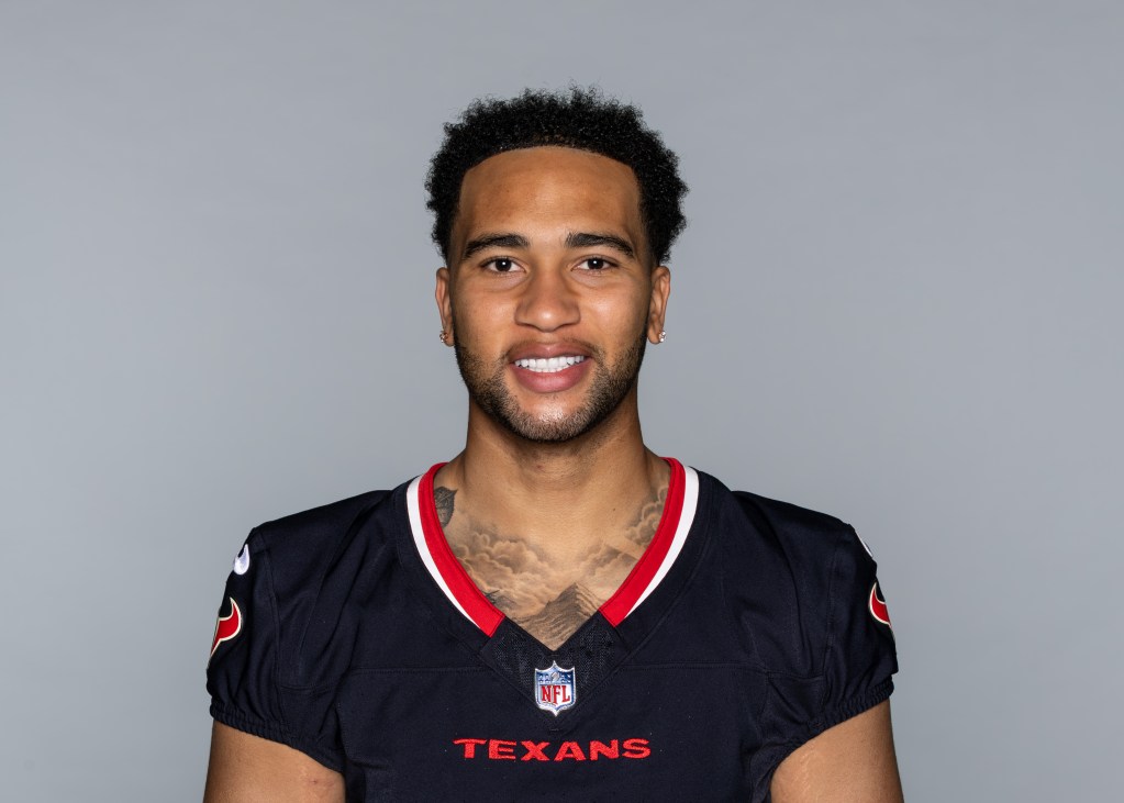 A smiling football player wearing a black NFL Texans jersey with the team logo visible.