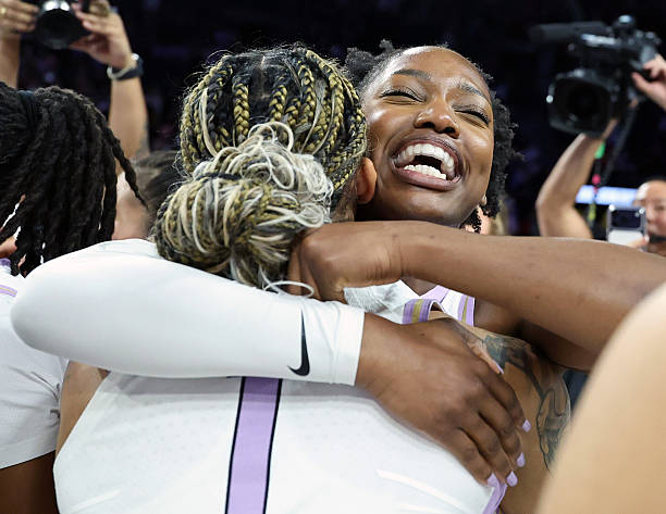 Two female basketball players embrace joyfully, celebrating a victory, with smiles and camaraderie.